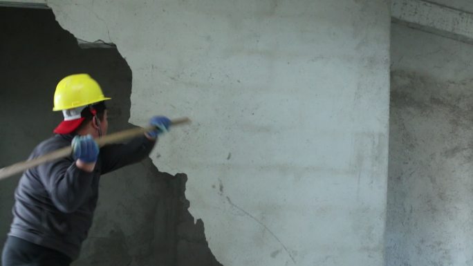 男子工人挥舞大锤击碎拆除建筑墙壁