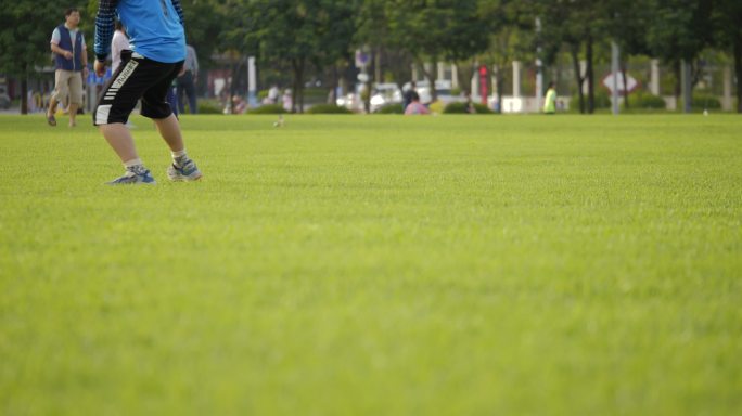 绿草坪上踢球的青少年