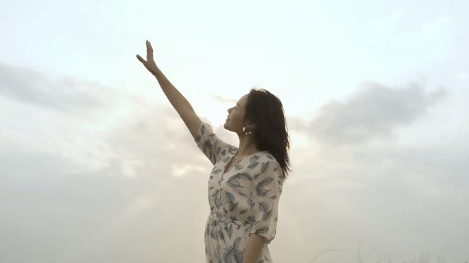 美女站在山顶吹着晚风看日落，唯美黄昏女孩