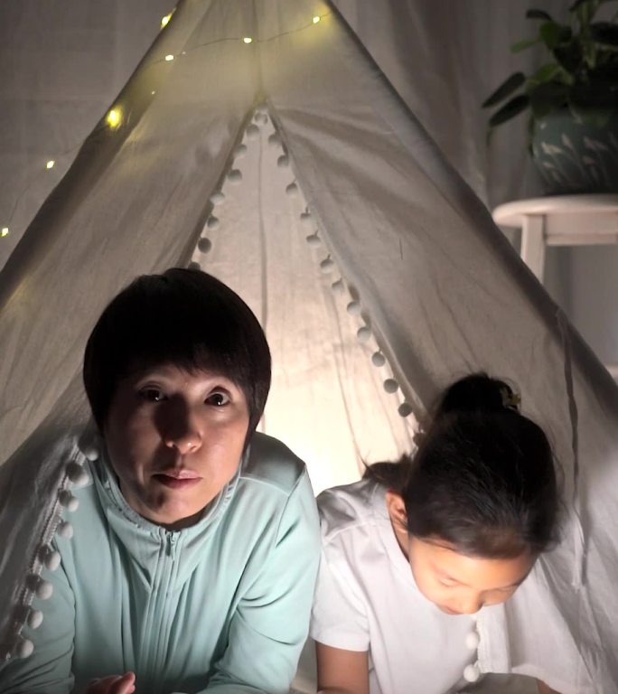 夜晚趴在帐篷里读书的母女