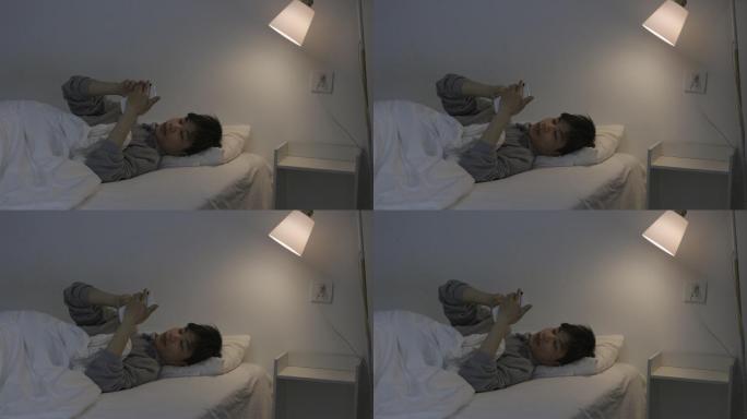 4K一个青年男性夜晚躺在床上玩手机
