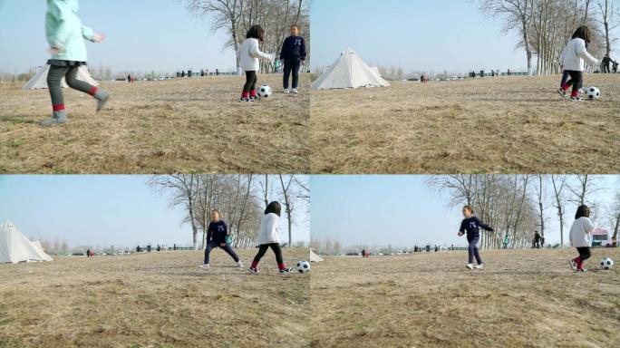 冬季在公园草坪上踢球的三个女孩
