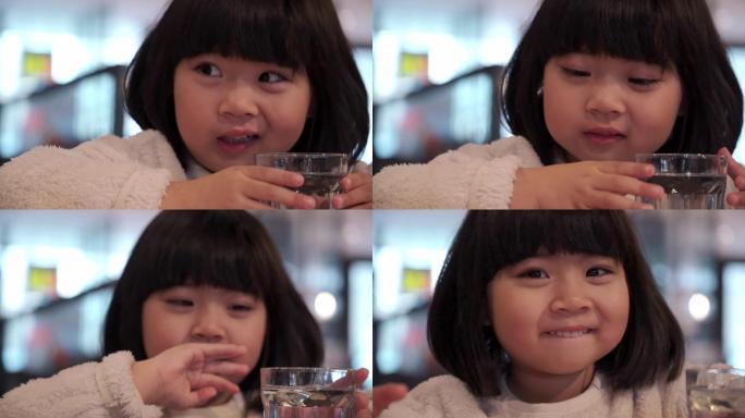 在餐厅喝水的亚洲女孩