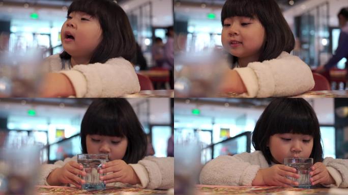 在餐厅喝水的亚洲女孩
