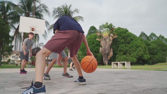 慢动作Z一代亚裔中国少年在周末早上和朋友练习篮球比赛时挑战球员并投篮