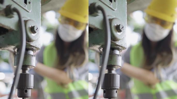 女工人操作支架钻孔机在金属板上打孔的垂直镜头