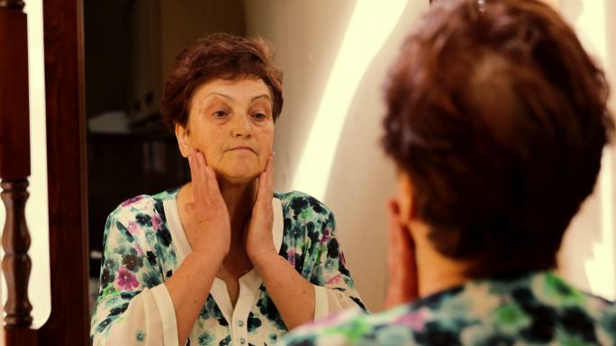 高加索老妇人在镜子里观察自己的脖子