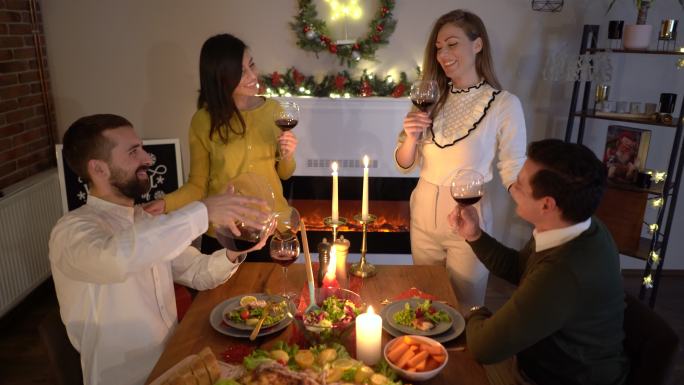 在家吃圣诞晚餐时，快乐的朋友们用红酒干杯