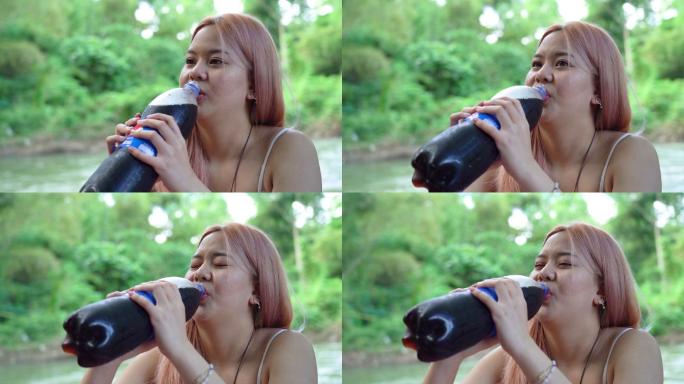 年轻女子从瓶子里喝黑苏打水