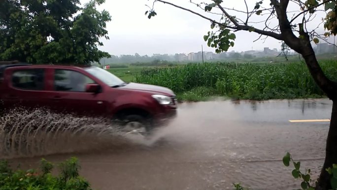 下雨天公路汽车过积水水花飞溅开过积水路段