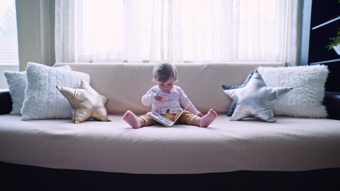 宝宝在沙发上看书，浏览图片。