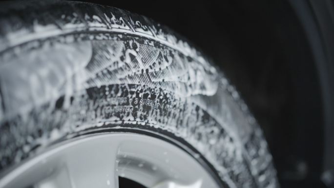 在汽车轮胎上喷涂清洁剂，用于清洁和打蜡轮胎。