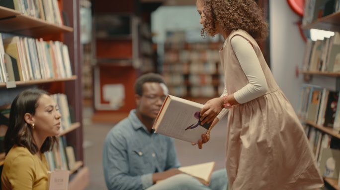 年轻的混血儿夫妇在图书馆看书时和女儿在一起。