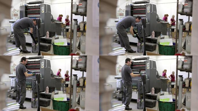 印刷厂的白人工人正在调整自动印刷机