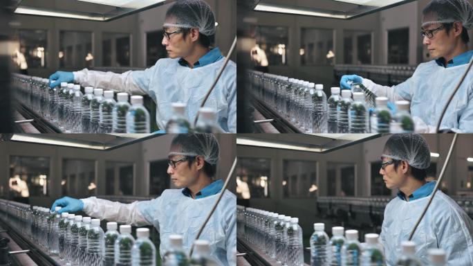 亚裔中国男性生产线工人，穿着干净的防护服，在瓶装厂矿泉水饮用水厂检查水瓶