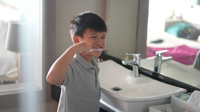 亚洲小孩在洁白干净的浴室刷牙。日常健康和牙齿护理的概念