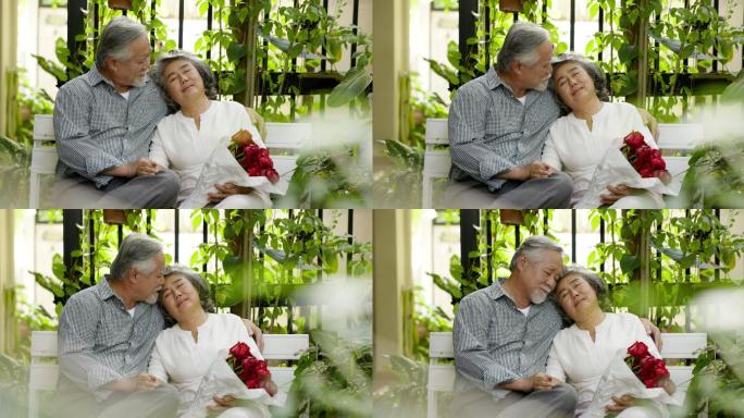 年迈的丈夫在家里用一束充满爱的玫瑰花给妻子惊喜。在结婚纪念日期间。老夫妇微笑着拥抱。