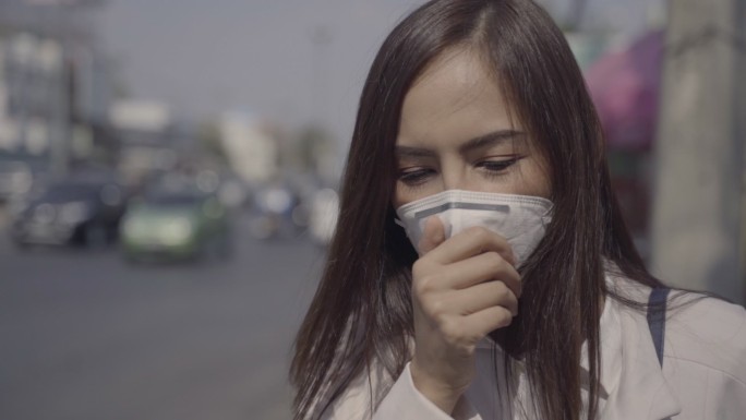 亚洲女人要去工作了。她戴着N95口罩。防止PM2。5灰尘和烟雾。她在咳嗽