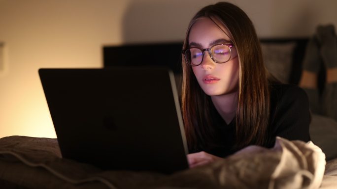 严肃的少女晚上在床上用笔记本电脑读坏消息4K
