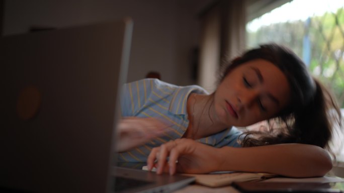 疲惫的年轻女子在家使用笔记本电脑观看在线课程