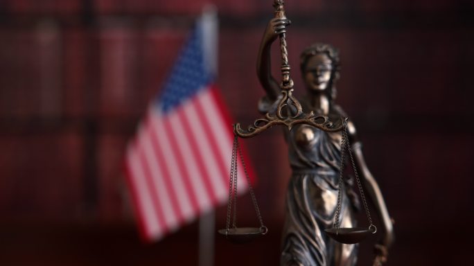 法律书籍和美国国旗前的正义雕像