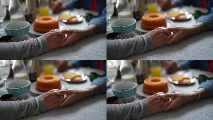家庭手牵手在家里为食物祈祷的特写镜头
