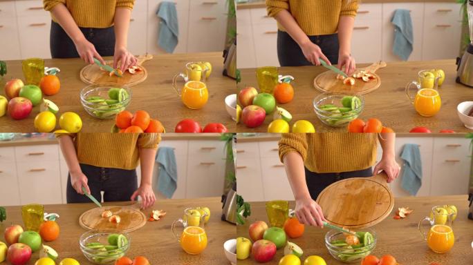 用女性的手切碎一个橘子，放在一个玻璃碗里，准备一份健康的水果沙拉