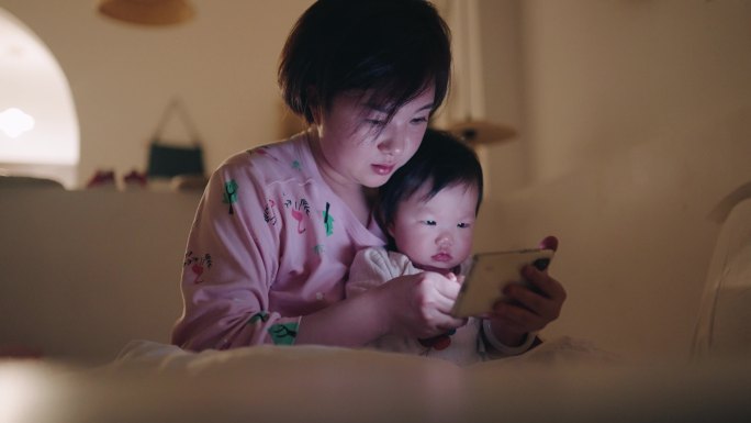 亚洲母女在床上使用智能手机