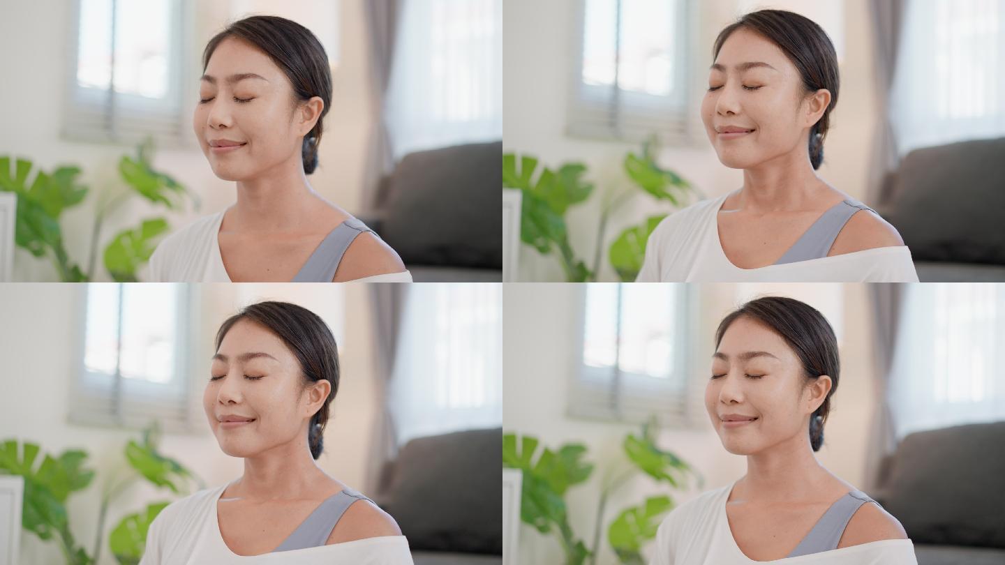 年轻漂亮的亚洲女性练习专注于呼吸的冥想,舒适地坐着,轻轻地闭上眼睛