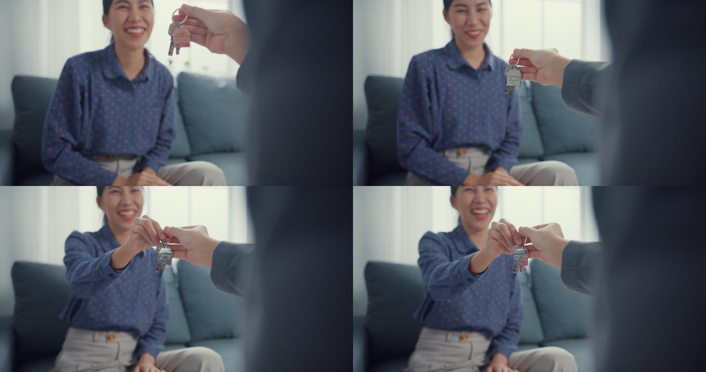 一位年轻的亚洲女性签署合同，在家里客厅的沙发上拿钥匙的特写镜头。