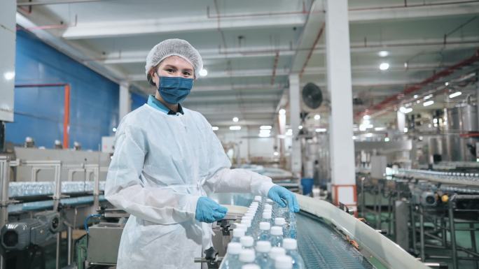 肖像亚裔中国饮用水厂生产线女工戴着PPE检查水瓶日常工作
