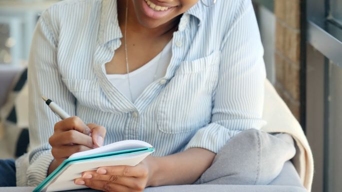 自信的年轻非裔美国女性在写日记时微笑