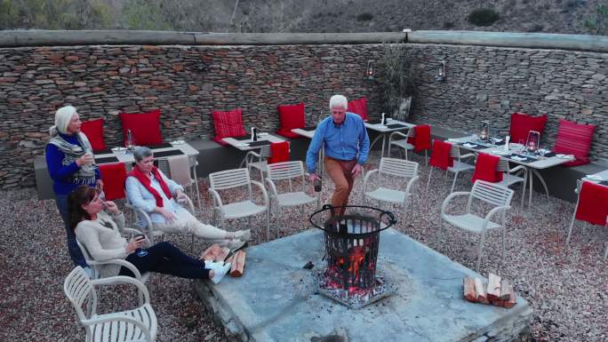 高级朋友们在酒店露台上放松，给火坑添柴