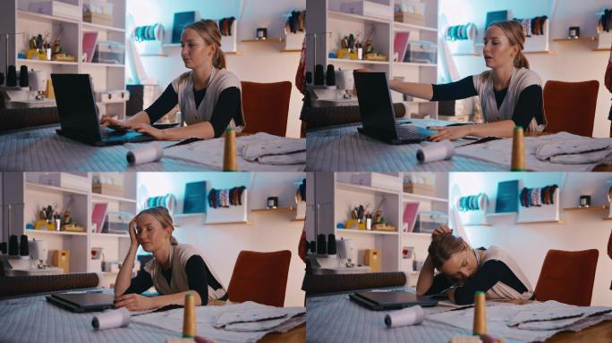 SLO MO年轻的女裁缝在工作室里用笔记本电脑工作时看起来很疲惫