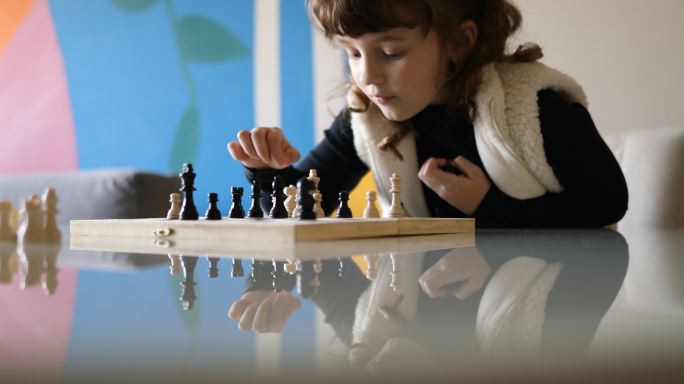 小女孩在下棋时思考和移动棋子