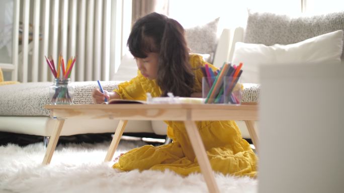小女孩在家客厅里画画和做作业