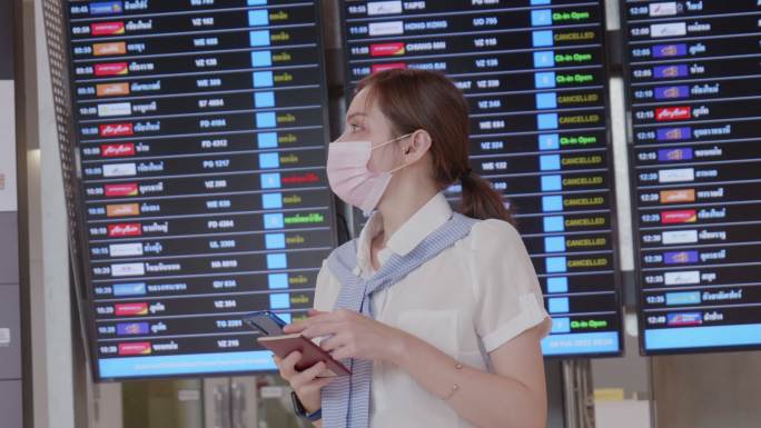 20-30岁的亚裔女性在机场使用智能手机穿着休闲服，在冠状病毒封锁和旅游重新开放后，2019冠状病毒