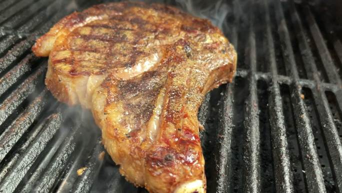 厚切生调味牛肉里贝耶牛排和有机胡萝卜放在木炭烤架上，火焰4K视频