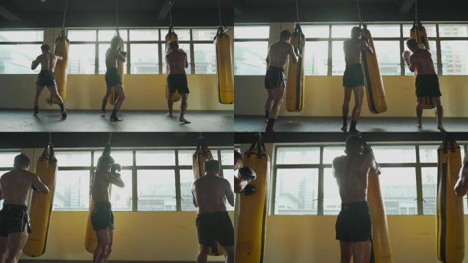 低角度后视极限运动亚洲男子泰拳拳击手连续打沙袋一起在健身俱乐部练习
