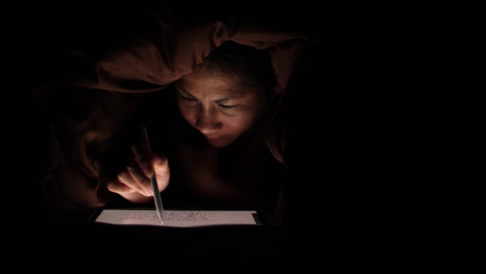 晚上在数字平板电脑上画画的女人