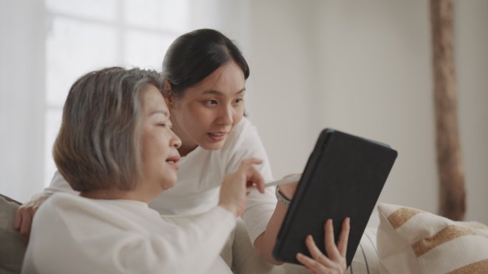 亚洲资深母亲和中年女儿在客厅使用手机