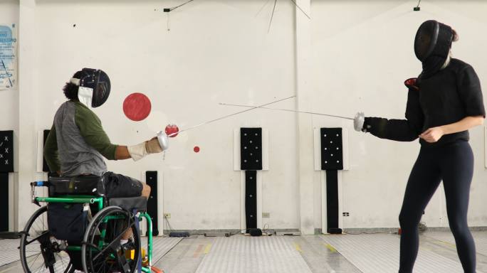 男轮椅击剑运动员与女教练一起训练