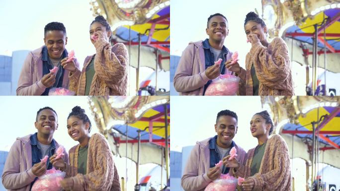 年轻的黑人夫妇在狂欢节上吃棉花糖，大笑