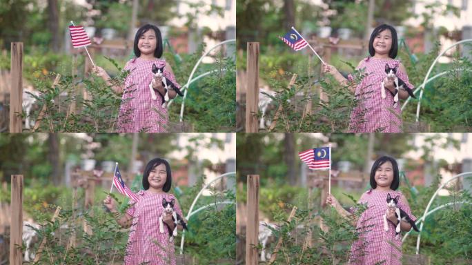 一名亚裔中国女孩，她的宠物猫在自家农场挥舞国旗