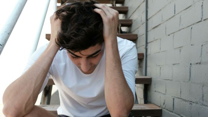 焦虑和抑郁的年轻成年男子独自坐着，心理健康，自闭症概念
