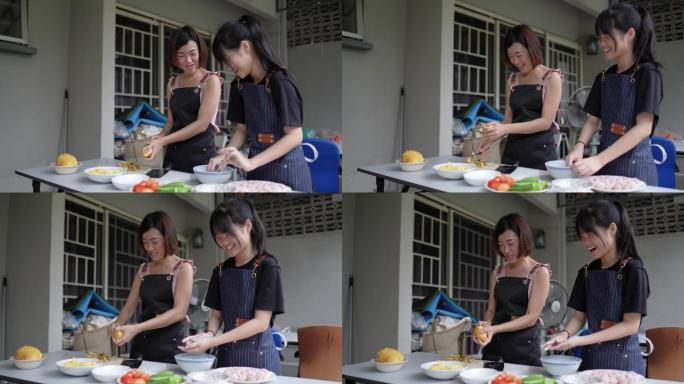 亚裔中国母亲和女儿在后院厨房准备食物。女儿正在向母亲学习