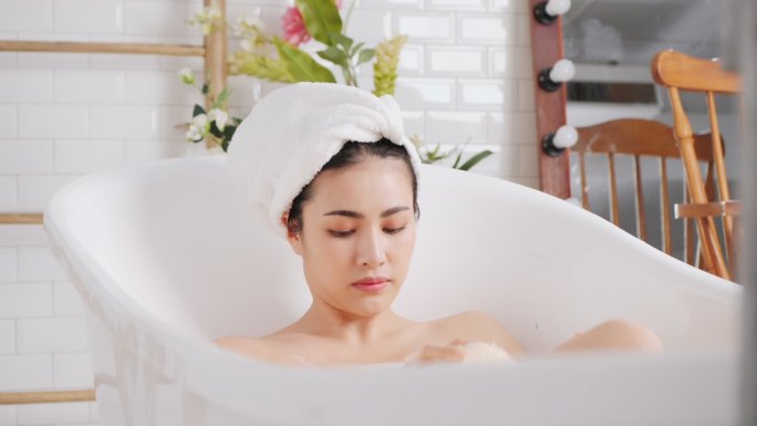 亚洲女性的身体护理是在浴室的浴缸里洗澡。