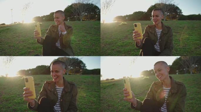 坐在公园草地上用手机打视频电话的女人