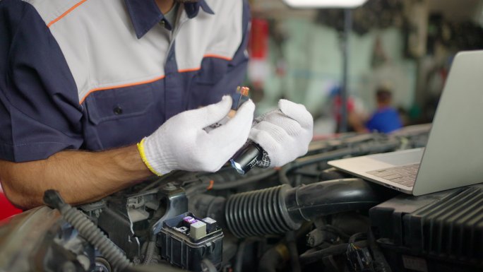 年轻的白人汽车修理工检查发动机和电气系统的状况，记录在清单上。检查发动机机油油位，检查电气保险丝。