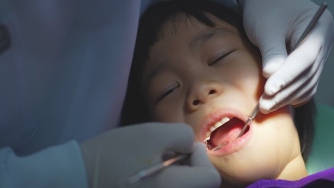 牙科医生的手正在牙科诊所为一名6岁的亚洲小孩做牙齿护理